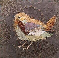 an embroidered bird sitting on top of a piece of fabric