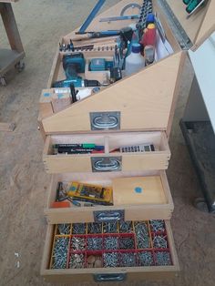 an open tool box sitting on the floor next to a workbench with tools in it