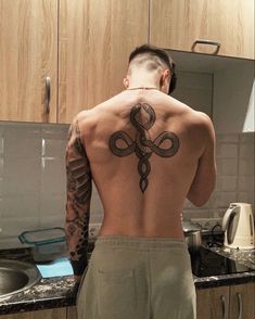 a man with a tattoo on his back standing in front of a kitchen counter top