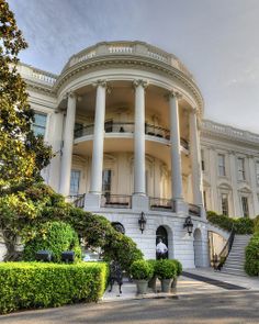 a large white building with columns on the front and stairs leading up to it's second floor