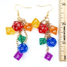 multicolored dice earrings with numbers hanging from gold plated earwires next to measuring ruler