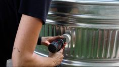 a man is using an electric drill to fix a metal tank