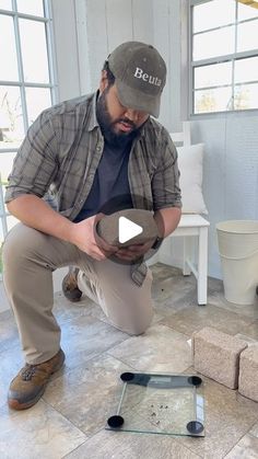 a man kneeling down on the ground holding something in his hands and looking at it