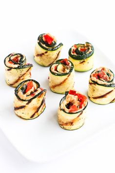 there are many small pieces of food on the plate, including zucchini rolls