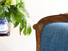 a blue chair next to a vase with flowers