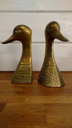 two brass ducks sitting on top of a wooden floor