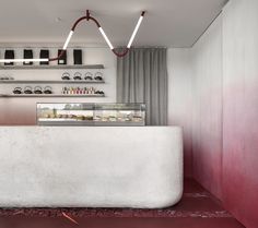 a white counter in a restaurant with red flooring and lights hanging from the ceiling