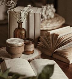 an open book sitting on top of a wooden table next to two vases filled with flowers