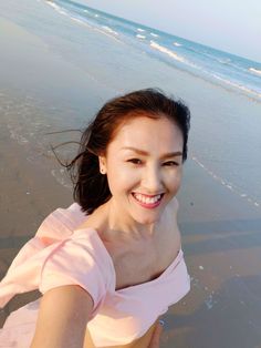 a woman standing on top of a beach next to the ocean