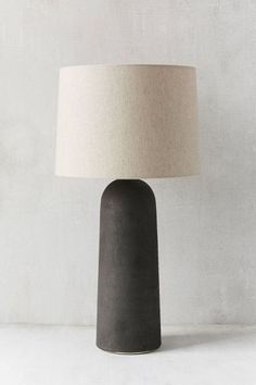 a black table lamp with a white shade on the base and a beige linen lampshade