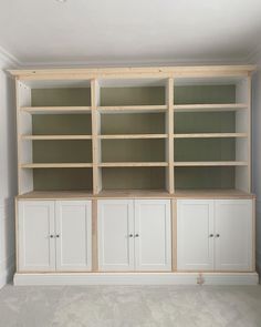 an empty room with white cupboards and shelves in the middle, all painted green