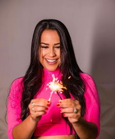 a woman in a pink shirt holding a sparkler