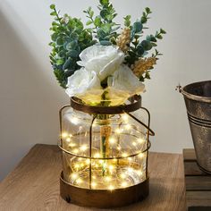 a vase with flowers and lights in it sitting on a table