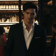 a man in a tuxedo standing next to a bar