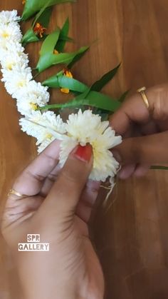 someone is arranging flowers on a table with green leaves and yellow flowers in the background