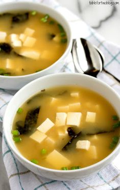 two white bowls filled with soup on top of a table