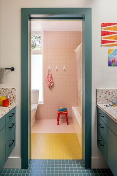 an open door leading to a bathroom with blue and yellow tiles on the floor, along with a red stool