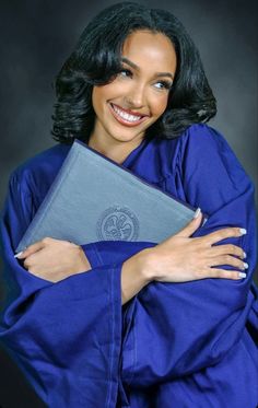 a woman in blue robe holding a book and smiling at the camera with her arms crossed