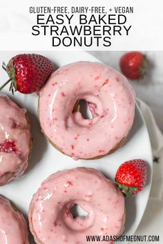 three strawberry donuts on a white plate with strawberries