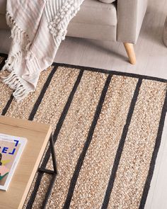 a living room area with a couch, coffee table and rug on the floor in front of it