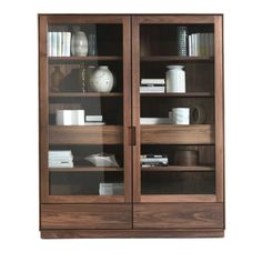 a wooden bookcase with glass doors and shelves filled with books, vases and other items