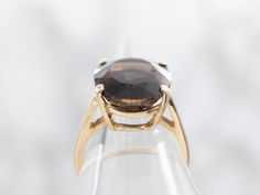 This ring is crafted in gleaming yellow gold and set with a stunning smoky quartz in the center of a classic solitaire design. The smooth lines and timeless look offer a classic and elegant appeal, perfect for any occasion.Metal: 10K Yellow GoldGem: Smoky Quartz 8.26 CaratsGem Measurements: 12.0 x 16.2 mm, OvalRing Size: 5.25Marks: "J-10K-L" Stamped on the inside band Classic Formal Rings With Faceted Details, Classic Formal Faceted Rings, Classic Smoky Quartz Rings For Formal Occasions, Classic Formal Smoky Quartz Rings, Classic Smoky Quartz Jewelry For Formal Occasions, Elegant Brown Rings For Formal Occasions, Classic Round Faceted Topaz Ring, Classic Faceted Round Cut Ring, Elegant Smoky Quartz Rings For Anniversary