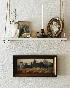 two shelves with pictures, candles and other items hanging on the wall next to each other