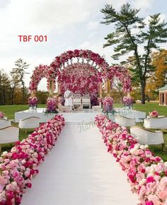 an outdoor ceremony setup with pink and white flowers on the aisle leading to the altar