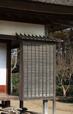 a wooden bench sitting in front of a white and brown building with wood slats on it's sides