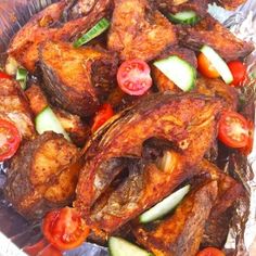 chicken with tomatoes, cucumbers and other vegetables on tin foil in a dish