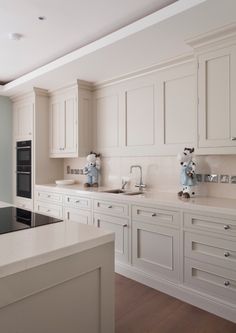 a kitchen with white cabinets and an island in the middle is seen from across the room