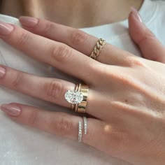 a woman's hand with three different rings on her fingers and one ring in the middle