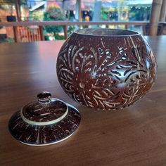 a brown vase sitting on top of a wooden table next to a container with lid