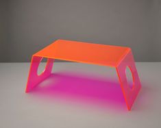 an orange and pink coffee table sitting on top of a gray floor with no one around it