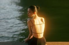 a woman standing next to a body of water with her back turned towards the camera