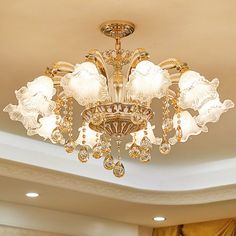 a chandelier hanging from the ceiling in a room with gold curtains and drapes