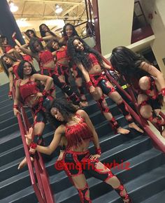 several women dressed in red and black are posing on stairs with their hands behind them