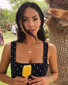 a woman standing next to a palm tree holding an ice cream