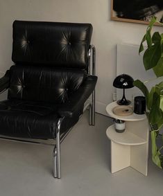 a black leather chair sitting next to a white table