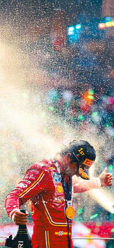 a man standing in the rain with his hand out and spraying water all over him