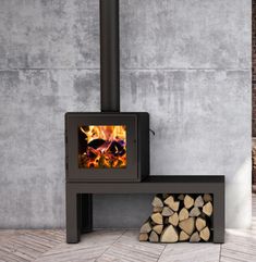 a wood burning stove sitting next to a pile of firewood on top of a wooden floor