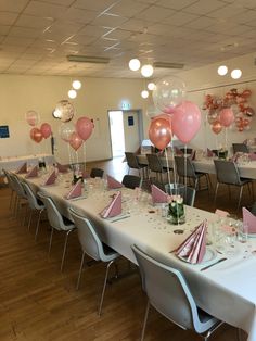 a room filled with lots of tables covered in pink and white balloons