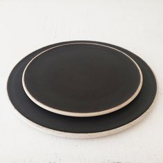 two black and white plates sitting on top of each other next to each other in front of a white wall