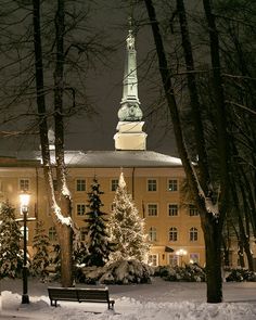 a snowy night in front of a large building with a steeple lit up at the top