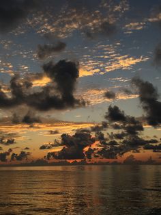 the sun is setting over the ocean with clouds in the sky and on the water