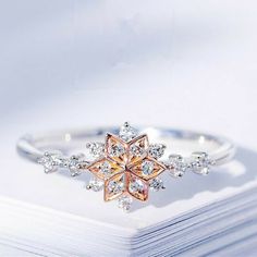 a white and pink diamond ring sitting on top of a book