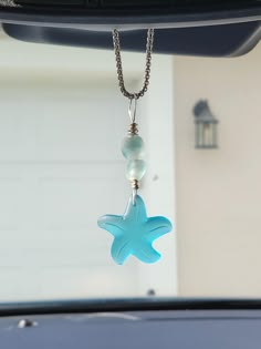 a blue starfish necklace hanging from the back of a car