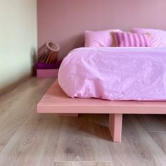 a bed with pink sheets and pillows on it