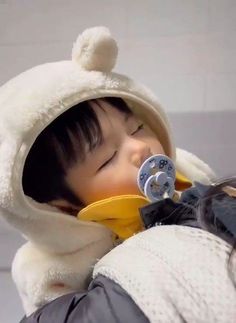 a young child wearing a hood and holding a pacifier