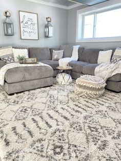 a living room with gray couches and white rugs on the floor in front of a large window